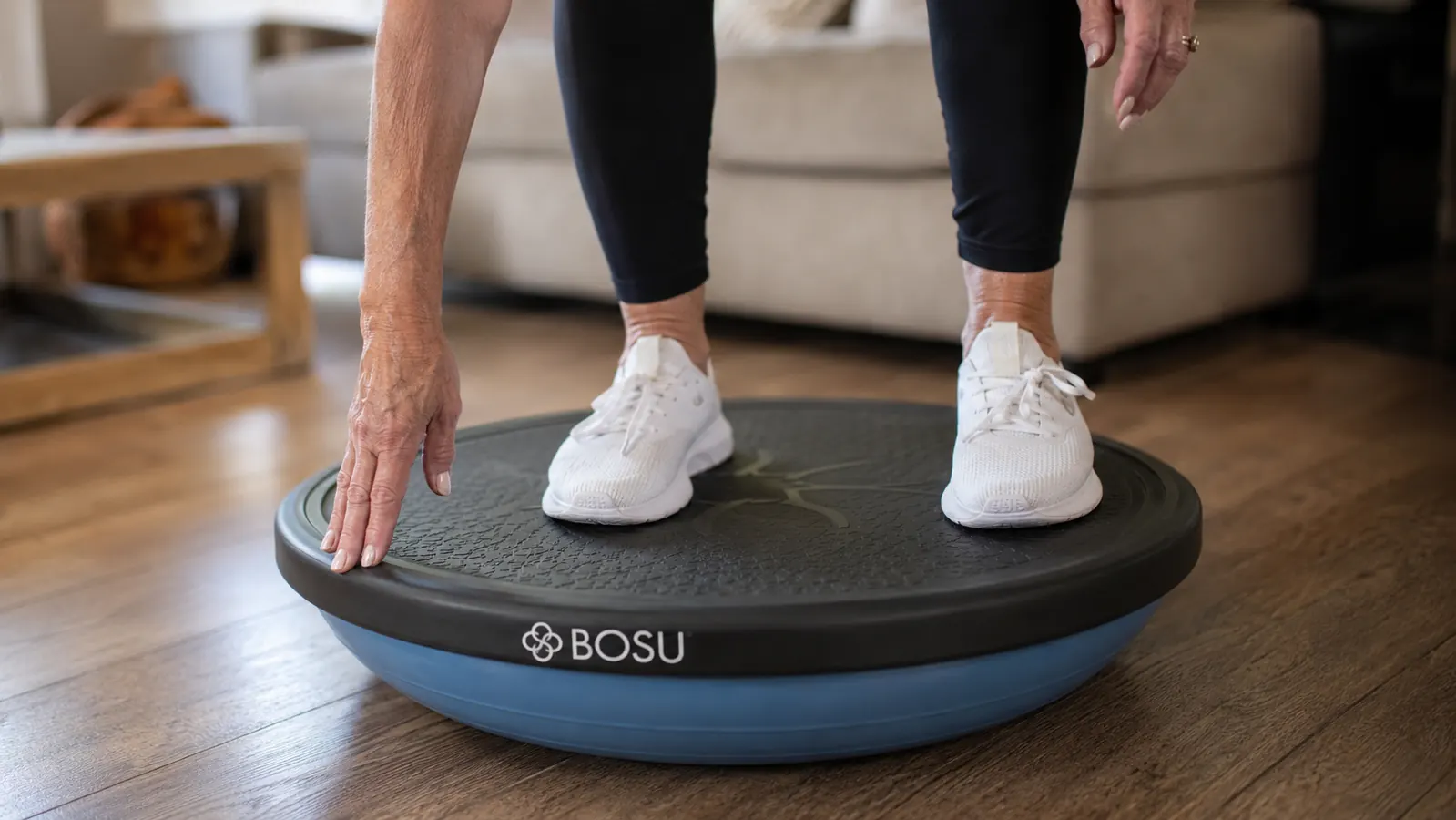 Close-up of a senior woman's feet on the flat platform side of a Bosu balance trainer, rubber grip surface visible