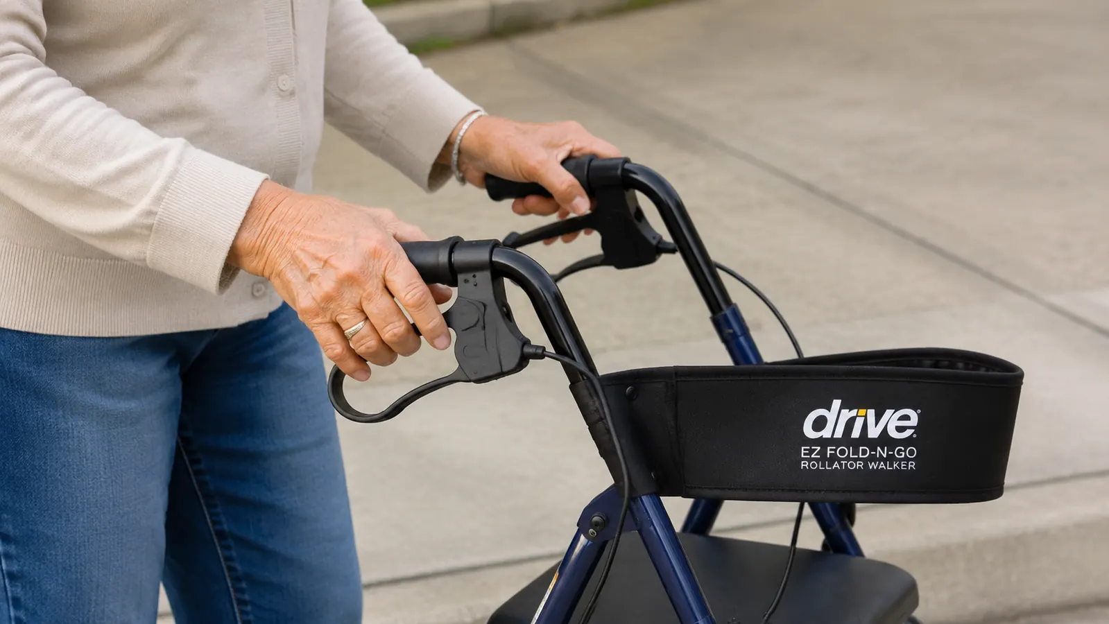 Hand squeezing a rollator brake lever showing the loop-lock mechanism engaged on a parked rollator