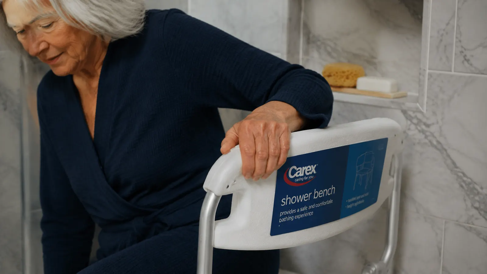 A woman's hand gripping a white shower bench armrest before stepping into a walk-in shower