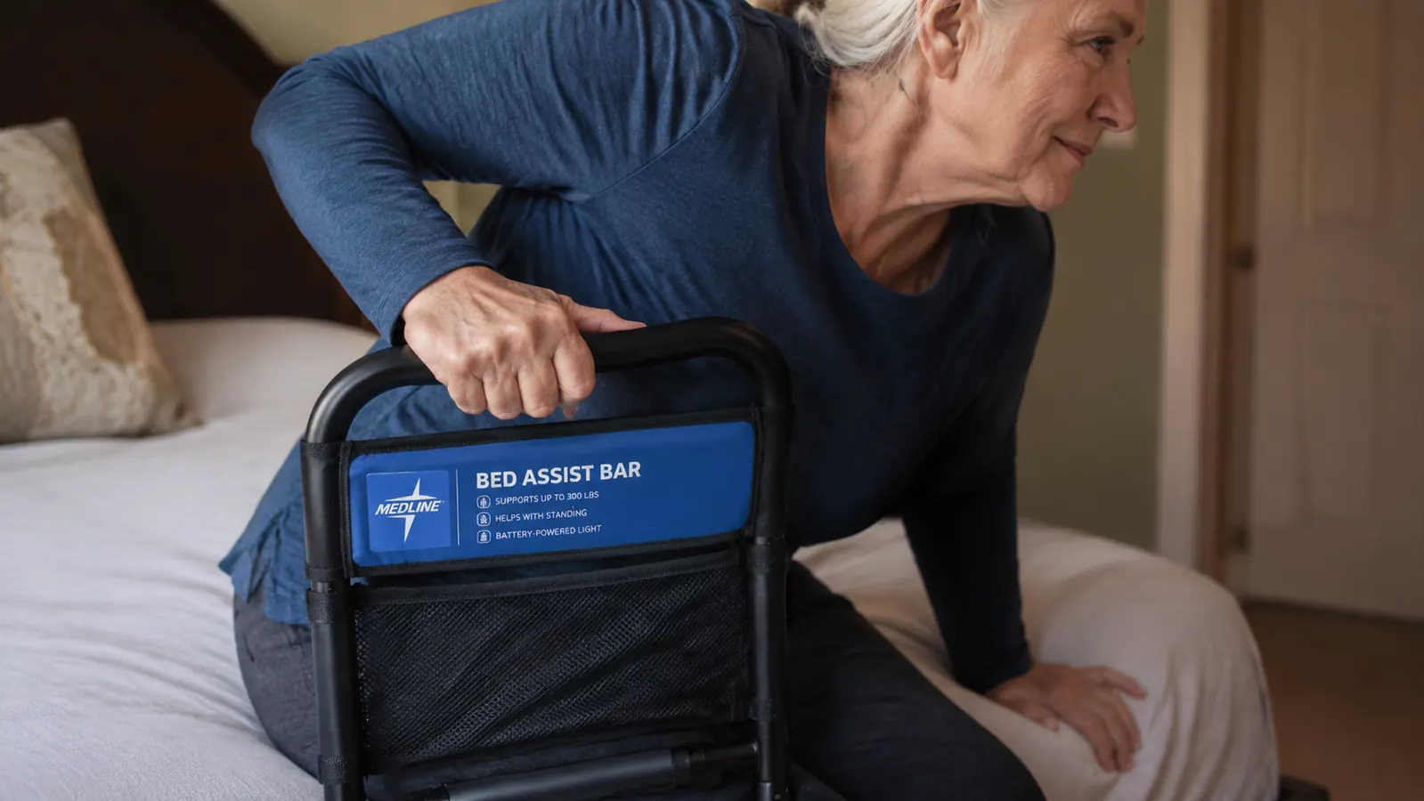 Close-up of a hand gripping a bed assist bar rail to push up from a mattress